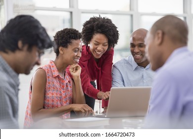 A Business Environment, A Light And Airy Workplace In The City.A Group Of People, Men And Women At A Meeting, Using A Laptop.