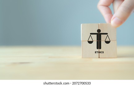 Business ethics concept. Business moral principles concept.  Hand holds the wooden cubes with "ETHICS" symbols on grey background and copy space. Banner for business integrity, good governance policy.