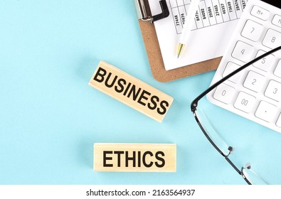 BUSINESS ETHICS text written on wooden block with clipboard ,eye glasses and calculator Business