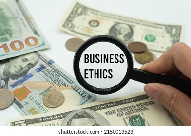 Business Ethics.Magnifying glass showing the words.Background of banknotes and coins.basic concepts of finance.Business theme.Financial terms.
