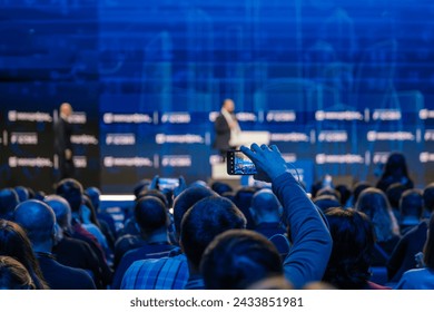 Business event attendees recording speaker on stage giving a professional presentation. - Powered by Shutterstock