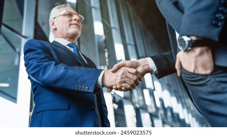 Business executive meeting a client at a coffee shop. Business working, success concept. Businessmen making handshake in the city - business etiquette, congratulation, merger and acquisition. - Powered by Shutterstock