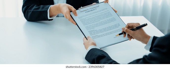 Business executive signing contract agreement document on the bale with the help from company attorney or lawyer service in law firm office. Business investing and finalizing legal processing. Shrewd - Shutterstock ID 2396305827