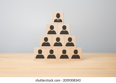 Business Executive Stacking Wooden Cube With People Icons On Them In Pyramid. Human Resources, Corporate Hierarchy And Multilevel Marketing Concept. Man Icon On Cube Wooden Block Stack In Pyramid