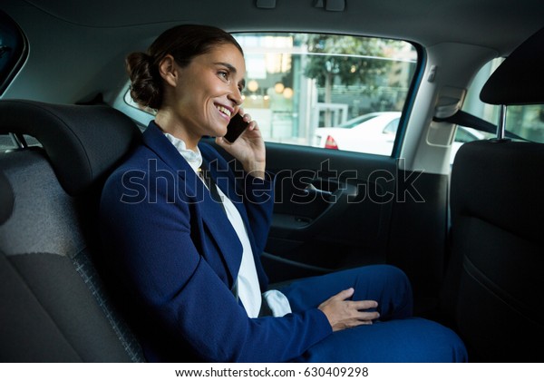 Business executive talking on mobile phone while\
traveling in car