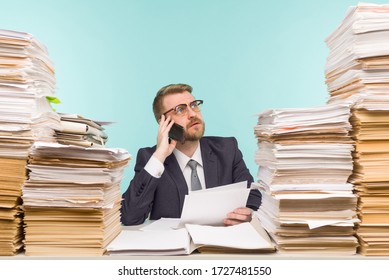 Business executive talking on the phone working in the office and piles of paperwork, he is overloaded with work - image