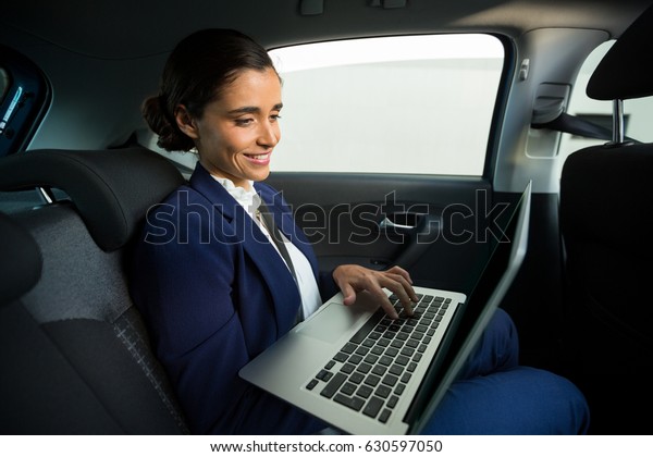 Business\
executive using laptop while traveling in\
car