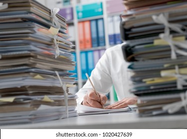 Business executive working in the office and piles of paperwork, he is overloaded with work