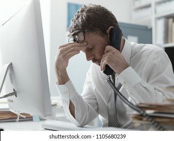 Business executive working in the office and receiving bad news on the phone, failure and crisis concept