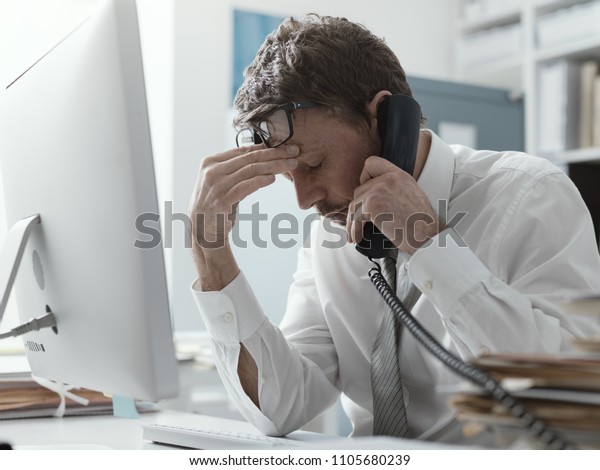 Business executive\
working in the office and receiving bad news on the phone, failure\
and crisis concept