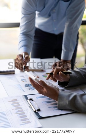 Business executives analyze data documents and calculating about fee tax at an office Image of business people working together analyzing calculations using a laptop calculator and graph