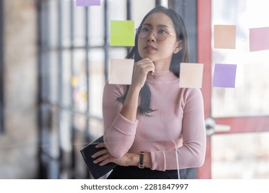Business female employee with many conflicting priorities arranging sticky notes commenting and brainstorming on work priorities colleague in a modern office.
 - Shutterstock ID 2281847997