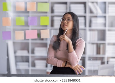 Business female employee with many conflicting priorities arranging sticky notes commenting and brainstorming on work priorities colleague in a modern office.
 - Shutterstock ID 2281848001