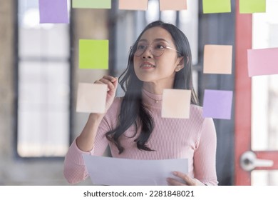 Business female employee with many conflicting priorities arranging sticky notes commenting and brainstorming on work priorities colleague in a modern office.
 - Shutterstock ID 2281848021