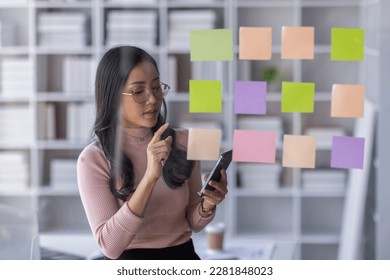 Business female employee with many conflicting priorities arranging sticky notes commenting and brainstorming on work priorities colleague in a modern office.
 - Shutterstock ID 2281848023