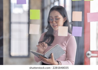 Business female employee with many conflicting priorities arranging sticky notes commenting and brainstorming on work priorities colleague in a modern office.
 - Shutterstock ID 2281848035