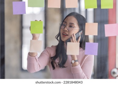 Business female employee with many conflicting priorities arranging sticky notes commenting and brainstorming on work priorities colleague in a modern office.
 - Shutterstock ID 2281848043