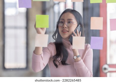 Business female employee with many conflicting priorities arranging sticky notes commenting and brainstorming on work priorities colleague in a modern office.
 - Shutterstock ID 2282265485