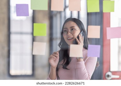 Business female employee with many conflicting priorities arranging sticky notes commenting and brainstorming on work priorities colleague in a modern office.
 - Shutterstock ID 2282626671