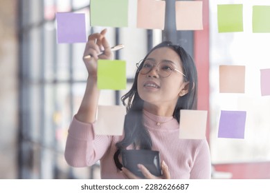 Business female employee with many conflicting priorities arranging sticky notes commenting and brainstorming on work priorities colleague in a modern office.
 - Shutterstock ID 2282626687