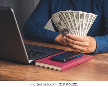 Business And Finance Concept. Businessman Holding US Dollars Banknotes While Sitting At The Table In The Office. Personal Loans And Payday Loans. Space For Text