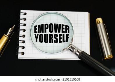 Business and finance concept. On a black surface there is a pen, a notebook and a magnifying glass. The inscription in the notebook - Empower Yourself