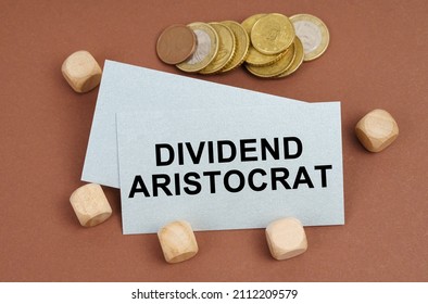 Business And Finance Concept. On A Brown Surface Are Coins, Cubes And A Business Card With The Inscription - Dividend Aristocrat