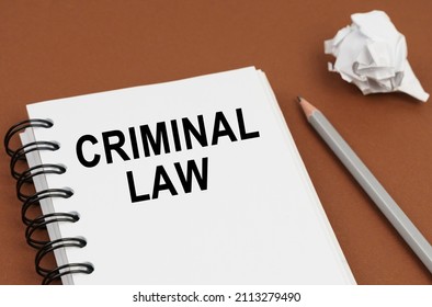Business and finance concept. On a brown surface lies a pen, crumpled paper and a notepad with the inscription - CRIMINAL LAW