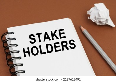 Business and finance concept. On a brown surface lies a pen, crumpled paper and a notepad with the inscription - STAKE HOLDERS - Shutterstock ID 2127612491