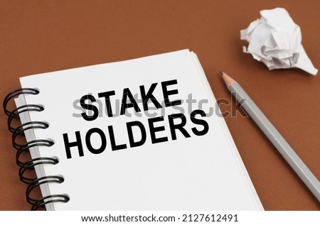 Business and finance concept. On a brown surface lies a pen, crumpled paper and a notepad with the inscription - STAKE HOLDERS