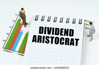 Business And Finance Concept. On The Chart There Are Miniature Figures Of Businessmen And A Notepad With The Inscription - Dividend Aristocrat