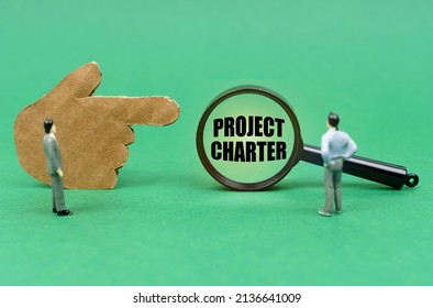 Business And Finance Concept. On The Green Surface There Is A Figure Of A Hand, Miniature Figures Of People And A Magnifying Glass With The Inscription - Project Charter