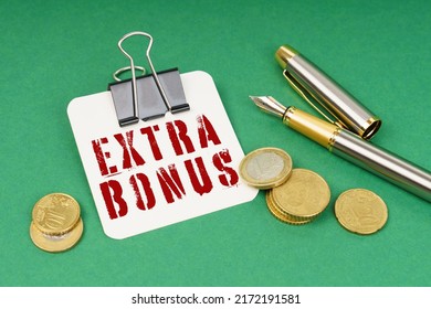 Business and finance concept. On a green surface, a pen, coins and a notepad with the inscription - Extra Bonus - Shutterstock ID 2172191581