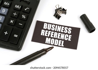 Business and finance concept. On a white table there is a calculator, a marker and a black plate with the inscription - Business Reference Model