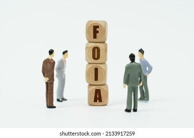 Business and finance concept. On a white background, figures of businessmen look at wooden cubes with the inscription - FOIA