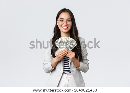 Business, finance and employment, entrepreneur and money concept. Successful young asian office manager, businesswoman showing earned cash, smiling satisfied as holding dollars