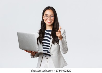 Business, Finance And Employment, Female Successful Entrepreneurs Concept. Smiling Pleased Businesswoman Praise Coworker Who Made Good Point, Pointing Finger Camera Satisfied, Hold Laptop