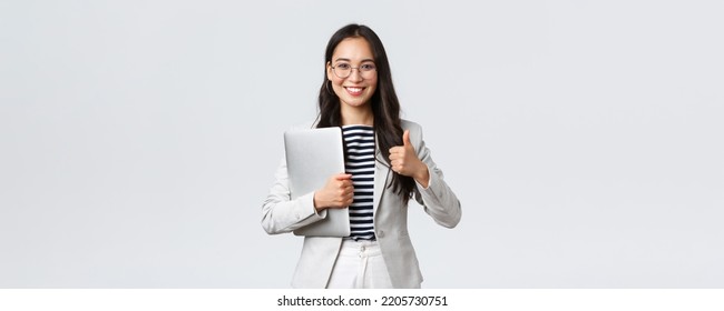 Business, finance and employment, female successful entrepreneurs concept. Confident good-looking therapist or businesswoman in white suit, holding laptop and showing thumbs-up - Shutterstock ID 2205730751