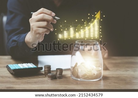 Business Finance and Money Save money concept, man calculating accounting numbers to estimate income expenditure and income His right hand holds a pen and draws a realistic gold graph growth.
