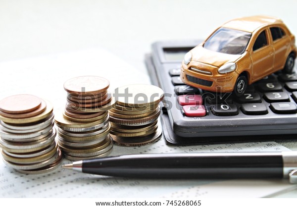 Business, finance, saving\
money or car loan concept : Miniature car model, coins stack,\
calculator and saving account book or financial statement on office\
desk table