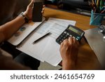 Business and Financial Planning Concept. Financial advisor hand planning and calculate budget, and tax. Professional Businesswoman use calculator and review annual report at home office.