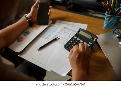 Business and Financial Planning Concept. Financial advisor hand planning and calculate budget, and tax. Professional Businesswoman use calculator and review annual report at home office.