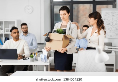 business, firing and job loss concept - colleague seeing off sad fired female employee with box of her personal stuff leaving office