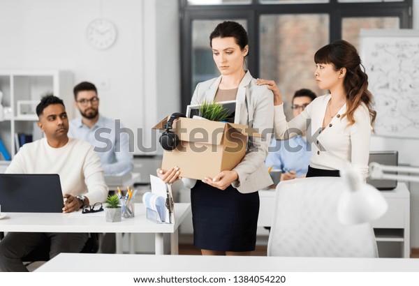 business, firing and job loss concept - colleague
seeing off sad fired female employee with box of her personal stuff
leaving office