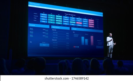 Business Forum Economics Conference Stage: Professional Speaker Concludes His Report With A Speech And Showing Infographics, Statistics On The Big Screen.