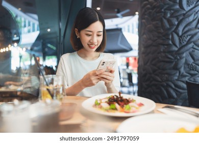 Business freelance young adult asian woman using smartphone and laptop work at cafe restaurant. Urban people lifestyle with modern technology on day. Digital nomad. Happy smile face. - Powered by Shutterstock