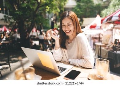 Business freelancer adult asian woman using laptop computer for work at sidewalk cafe. Happy and smile face. Urban people lifestyle with modern technology on day. - Shutterstock ID 2122196744