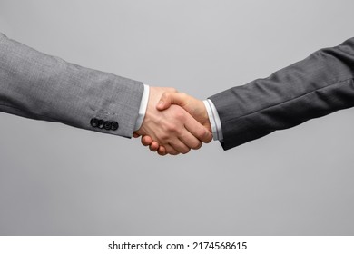 Geschäfts-, Gesten- und Partnerschaftskonzept - Handshake von zwei Geschäftsleuten auf grauem Hintergrund