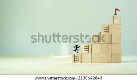 Business goal success concept. Rises up stairs to goal and achieve business success.Personal growth. Initiation for planning to reach target. Flag target aim icon on wooden cubes with grey background.