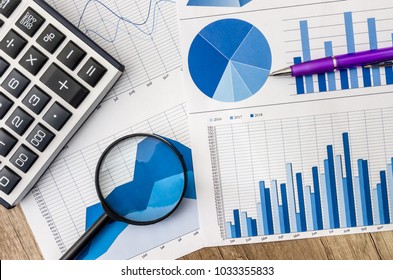 Business graph with magnifying glass and calculator pen on table